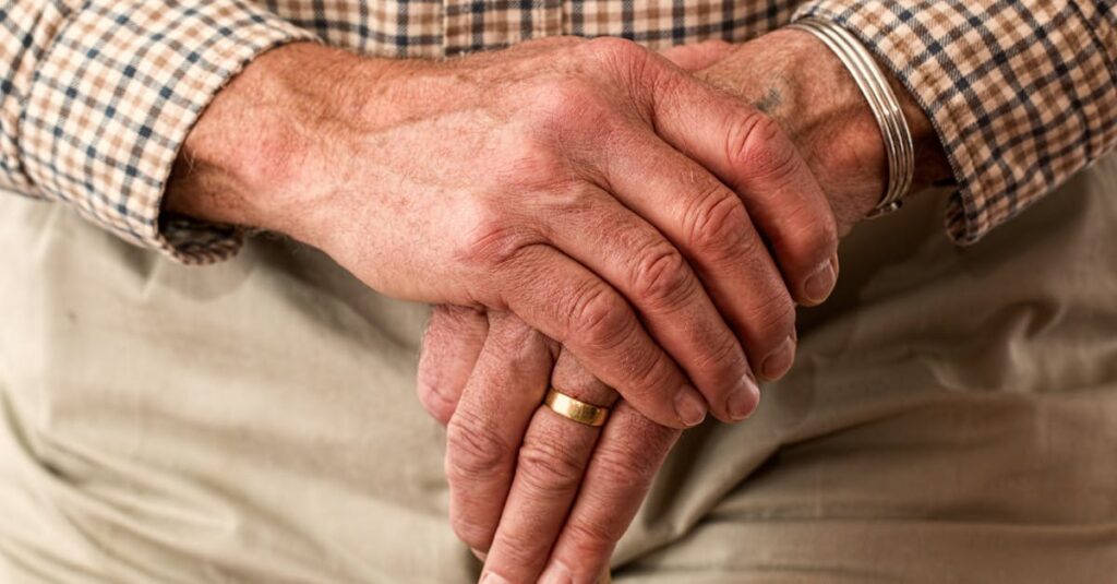 A detailed image of elderly hands clasping a wooden cane, symbolizing aging and support.
