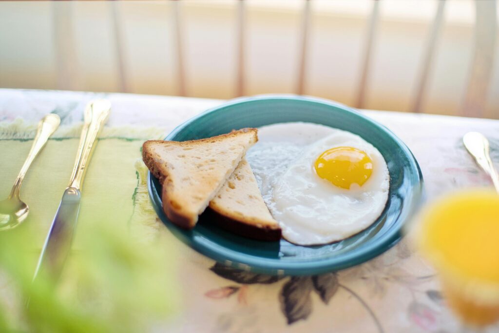 A classic breakfast setup with toasted bread and fried egg on a ceramic plate.