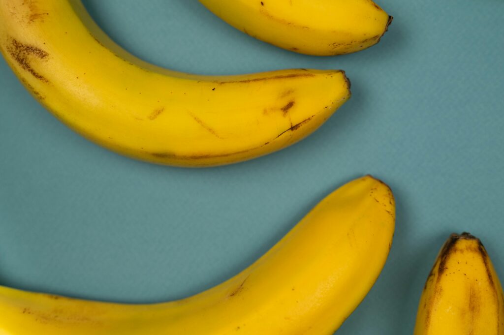 From above of tasty ripe bananas with blots on smooth yellow peel on blue background