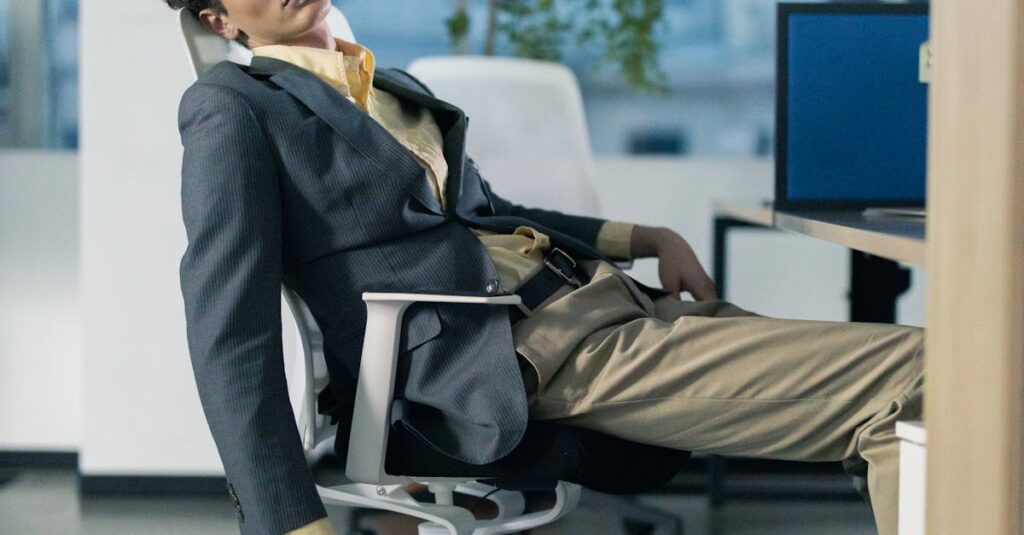 Tired businessman slumping in office chair among scattered paperwork in modern office.