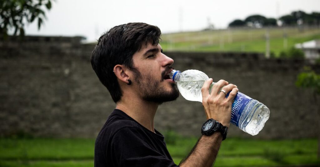 A young man drinks bottled water outside, staying hydrated and refreshed.