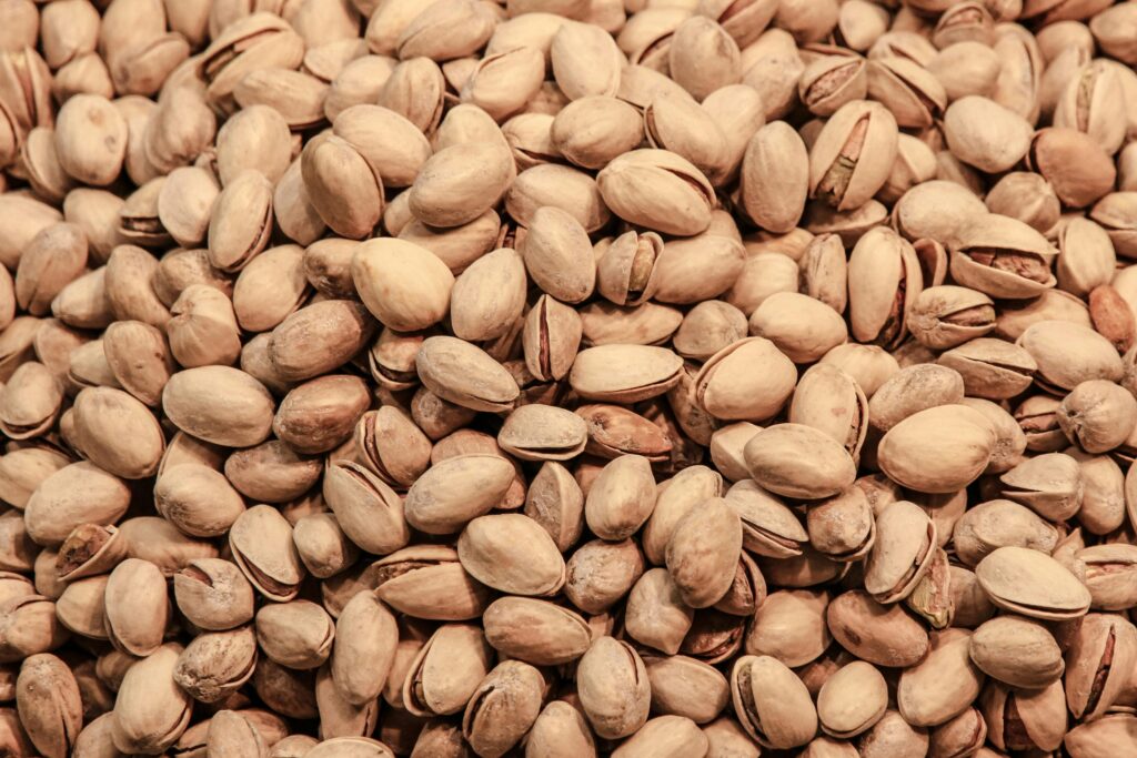 A detailed close-up image of pistachio nuts, showcasing their natural texture and earthy tones.