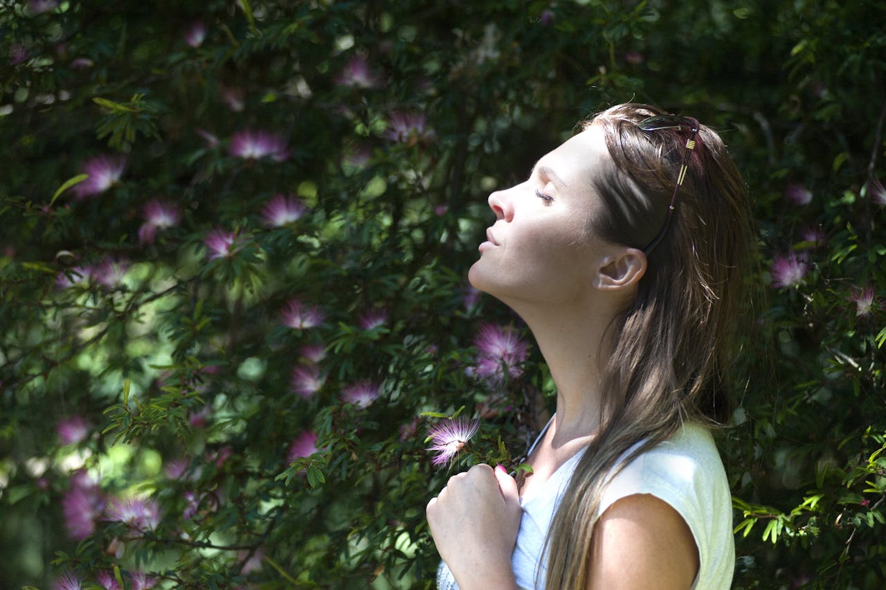 Services A woman enjoying a serene moment in a sunlit garden, surrounded by vibrant flowers.