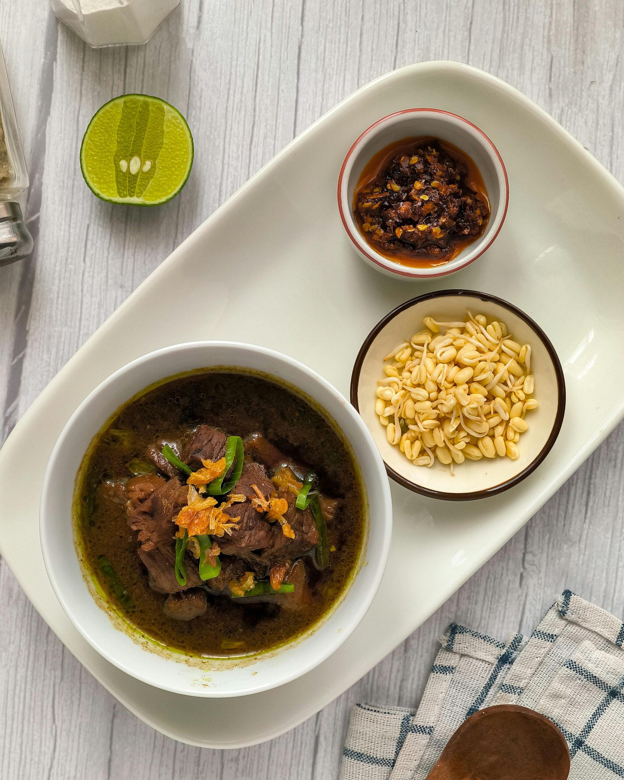 Delicious traditional Indonesian beef noodle soup served with sambal and crackers, perfect for a hearty meal.