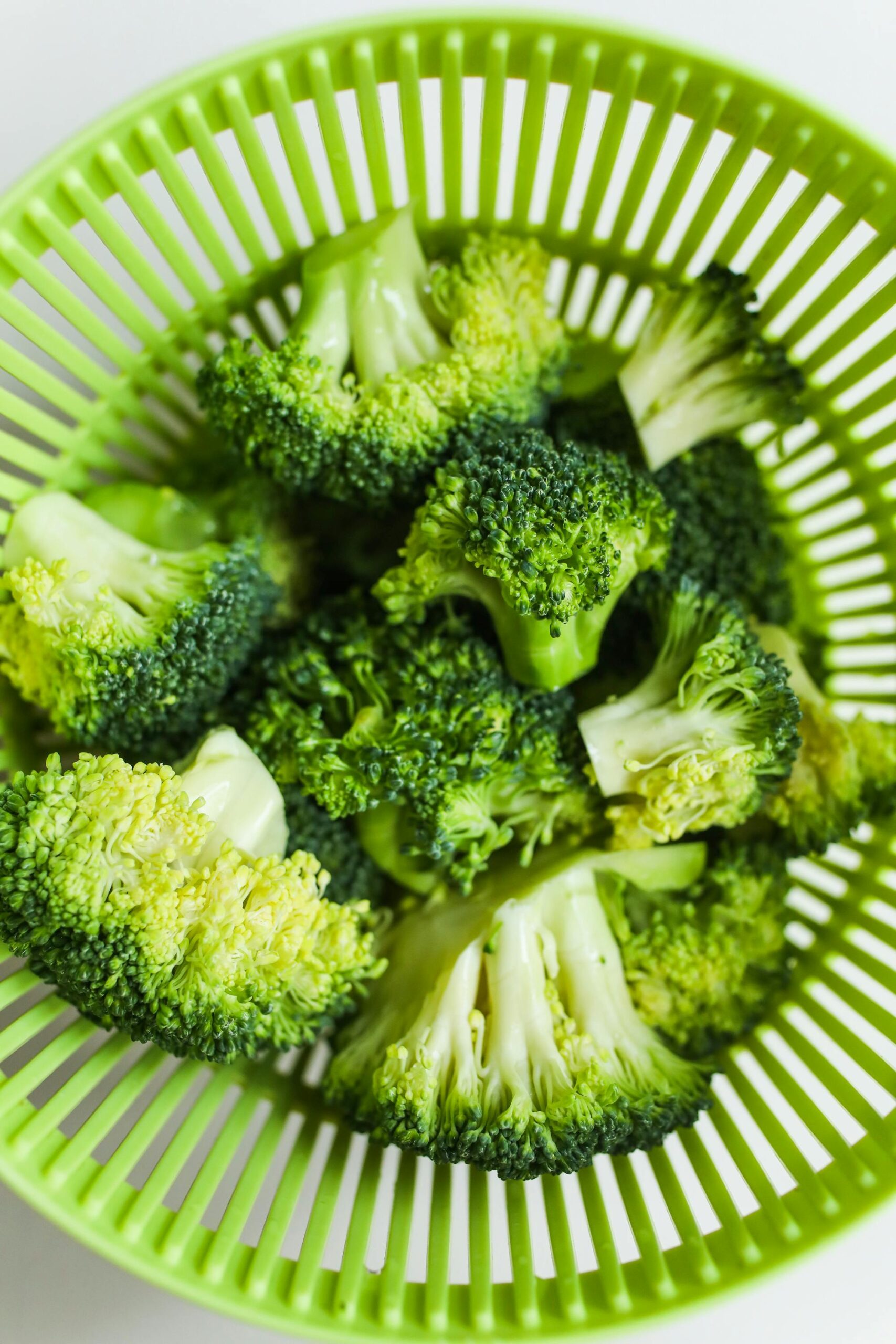 Vibrant fresh broccoli florets in a green colander, perfect healthy ingredient
