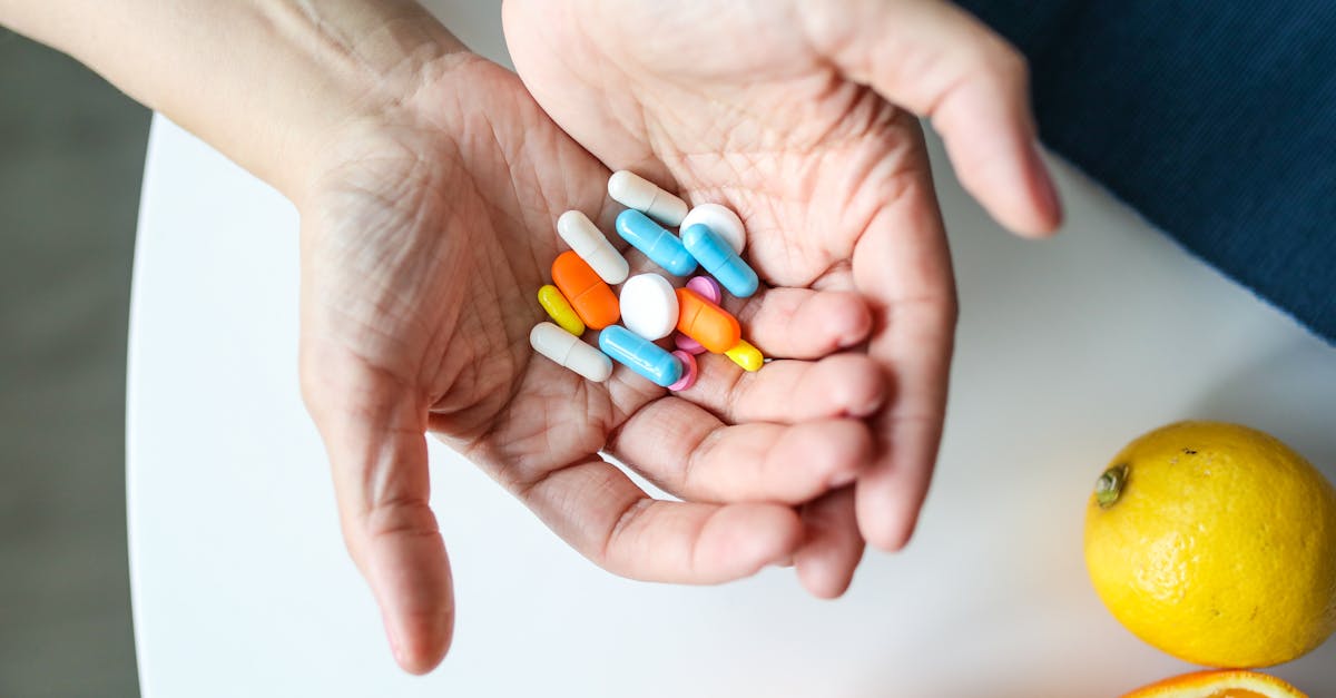 Close-up of hands holding multicolored pills with oranges, symbolizing health and nutrition.